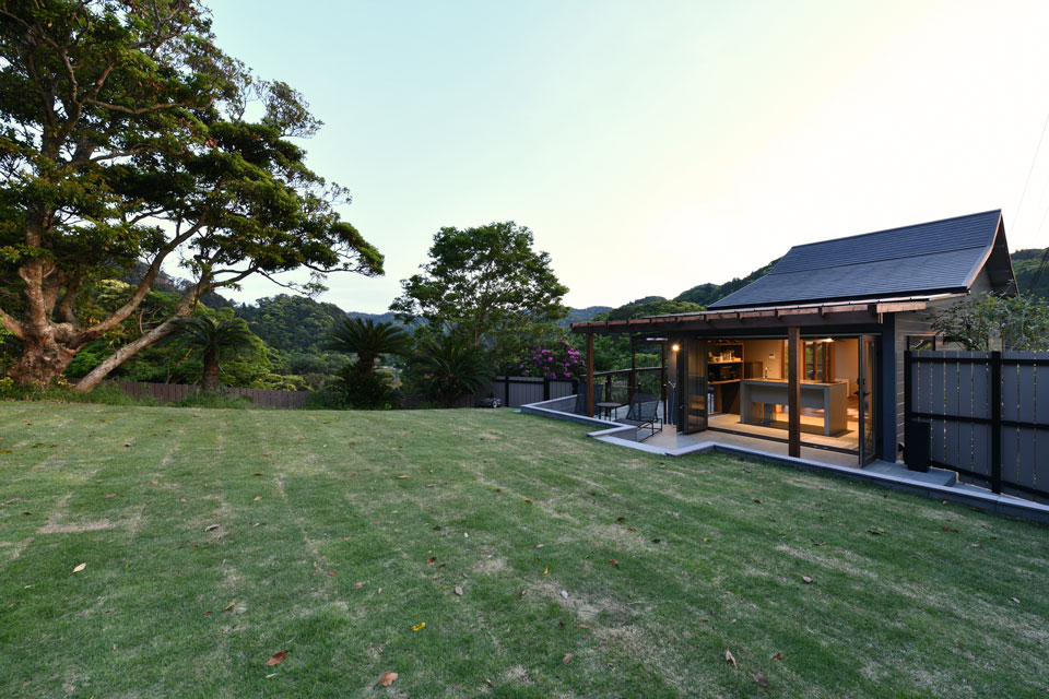 木々に囲まれたBON-MAL TREEの建物と芝生の庭